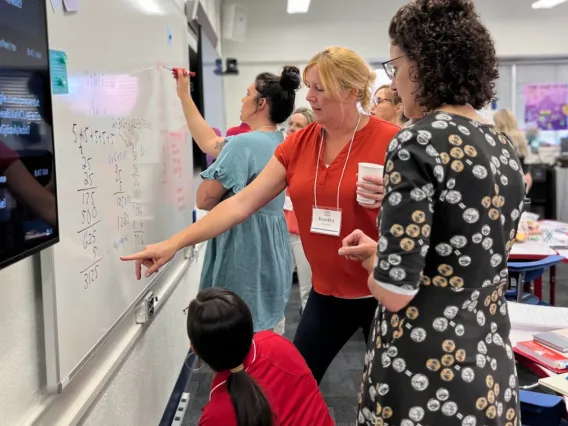 Teachers collaborating on a project while writing on a whiteboard