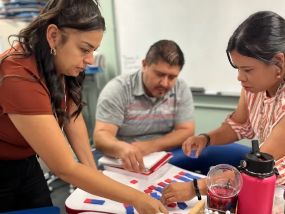 Three teachers collaborating with manipulatives provided to in person attendees