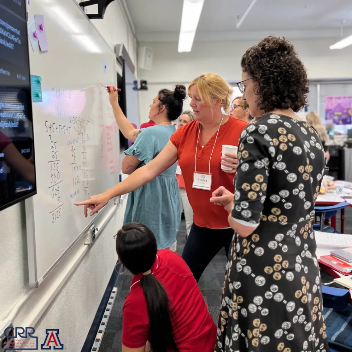 Teachers collaborating on a project while writing on a whiteboard