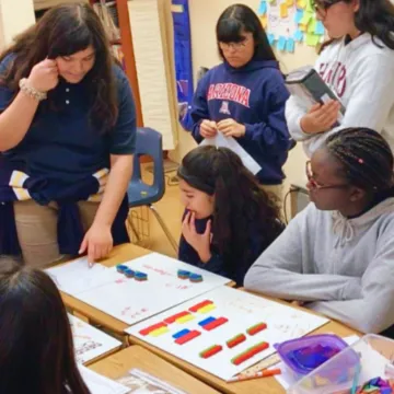 Teacher helping group of students with the use of manipulatives